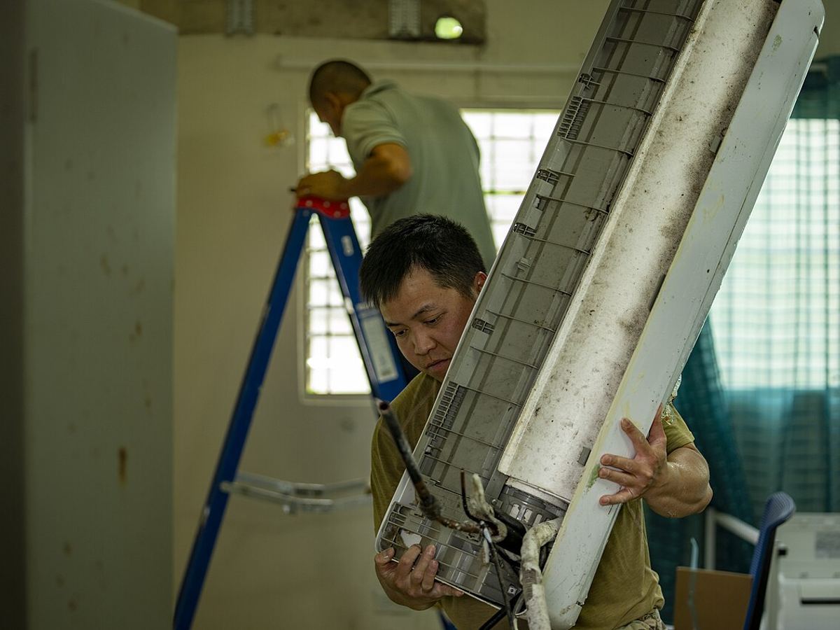 Technician removing an old split AC indoor unit